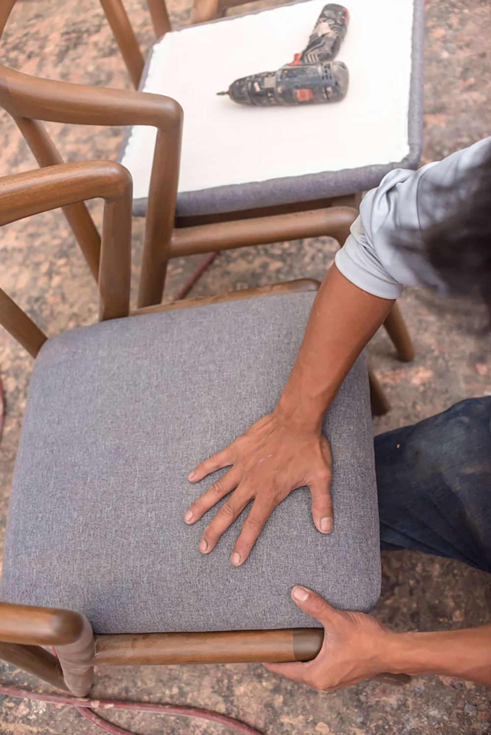 An upholsterer fits a cushioned pad into a wooden chair