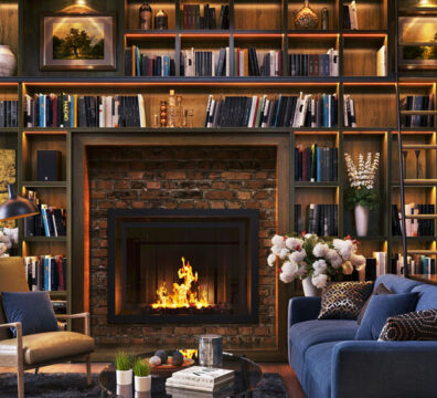 Home library lined with wood walls, blue sofa and a fireplace