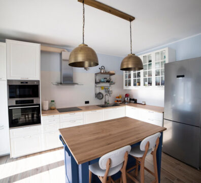 Kitchen with white cabinets, blue island and butcher block counter